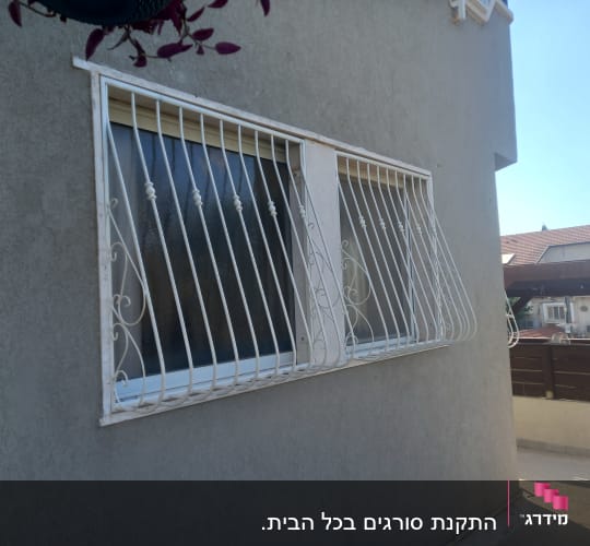 סורגי מתכת לבנים על חלון קיר חיצוני